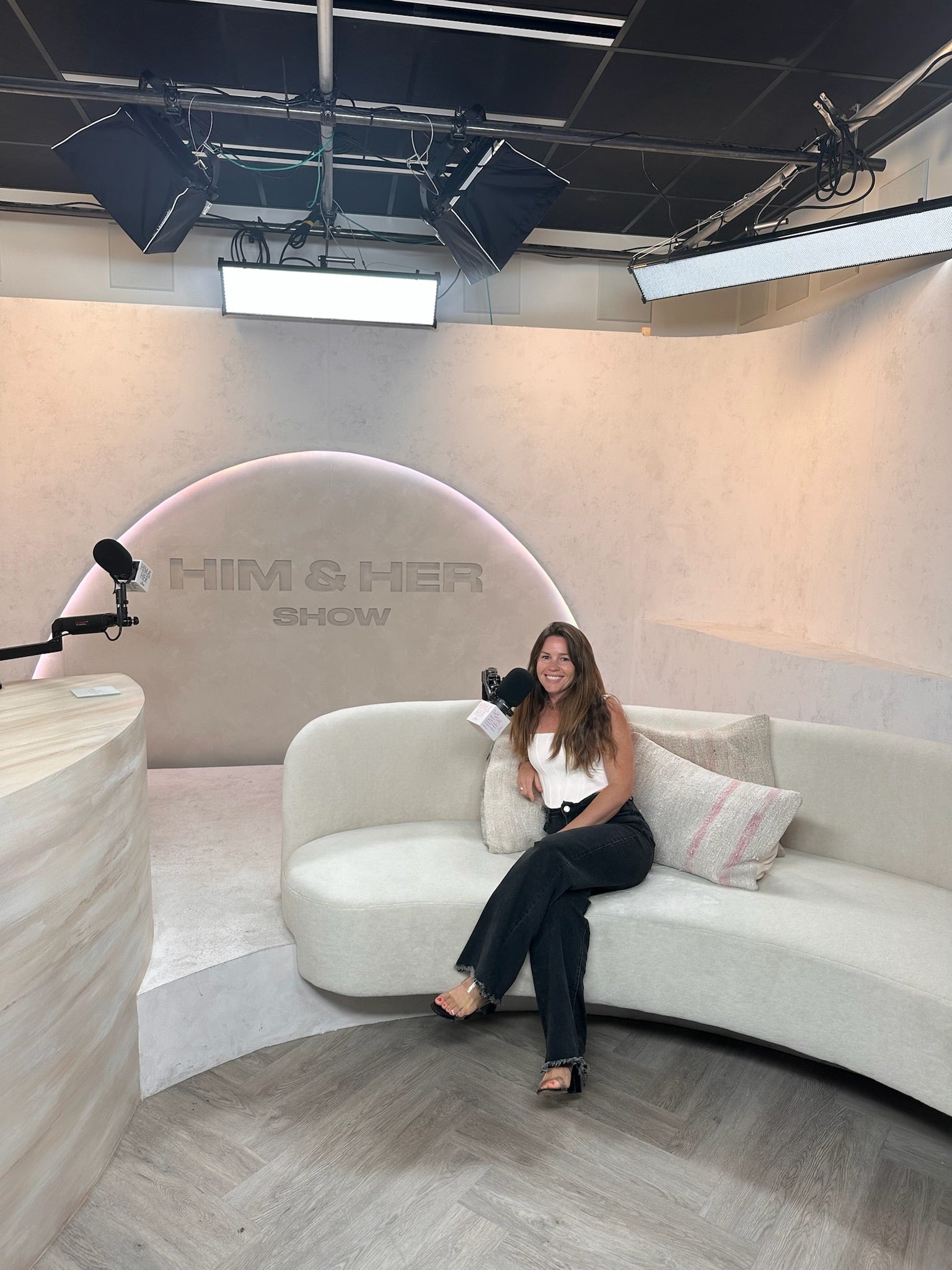 Morgan sitting on a white couch in a studio during the ‘Him & Her’ show.